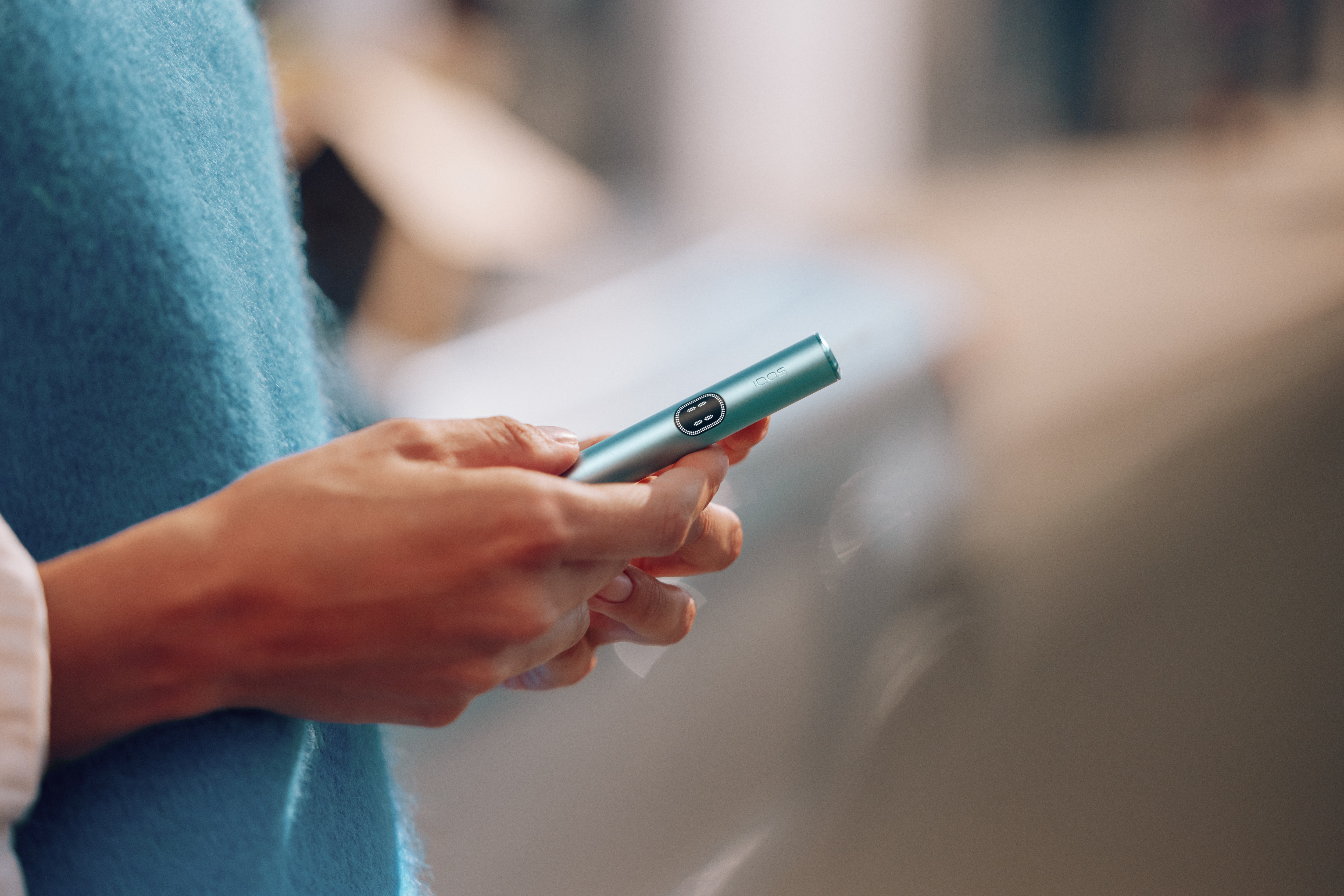 Mujer sujetando un IQOS azul 