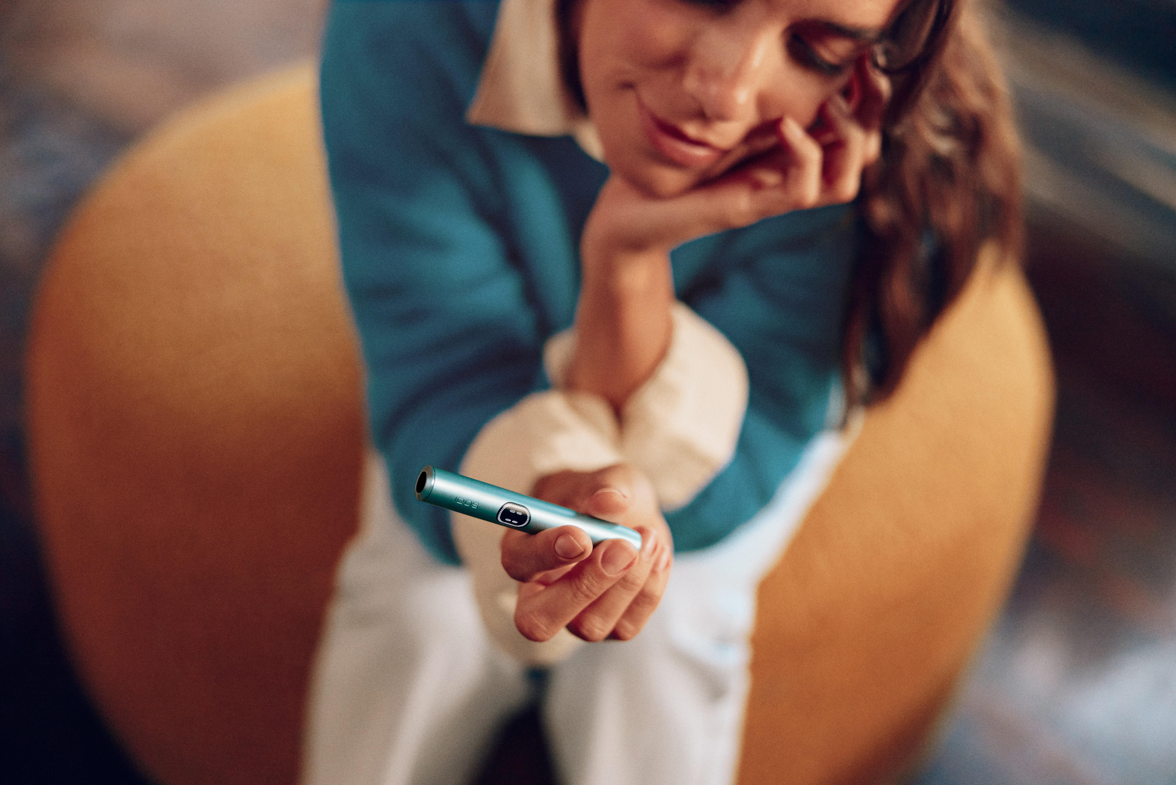Mujer sentada sujetando un IQOS