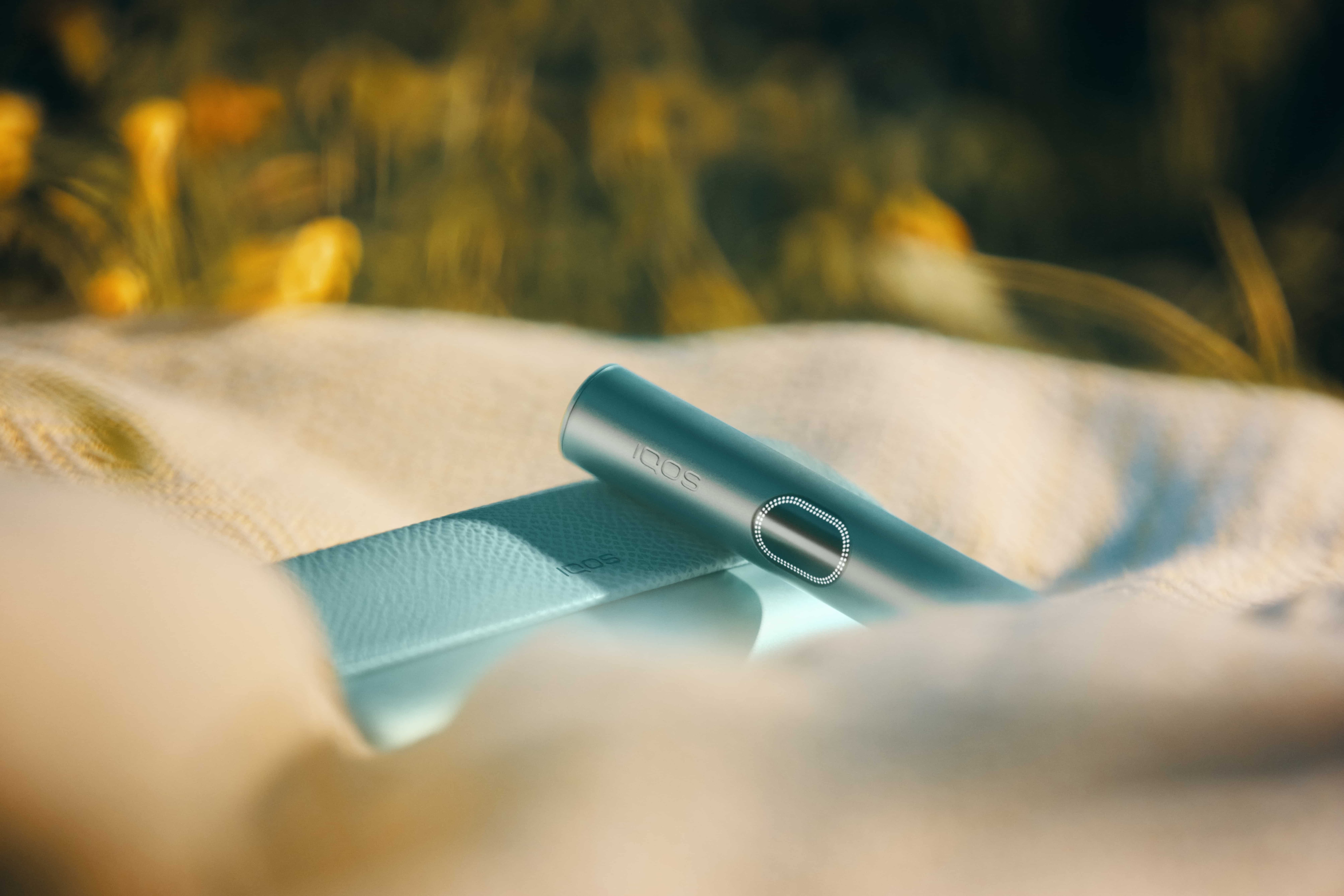 Dispositivo IQOS ILUMA i PRIME sobre un mantel de picnic en la naturaleza