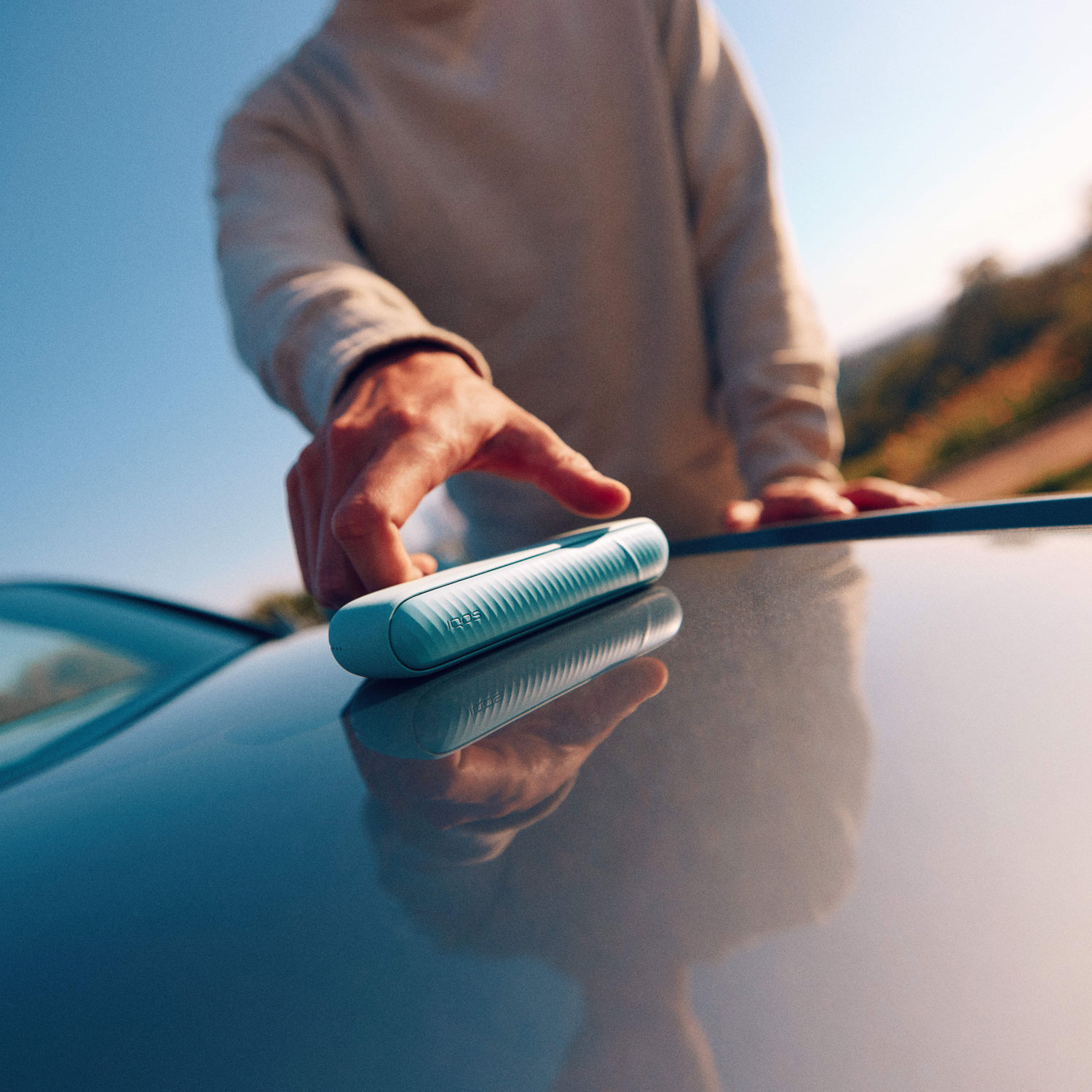 Persona cogiendo un IQPS del capó de un coche