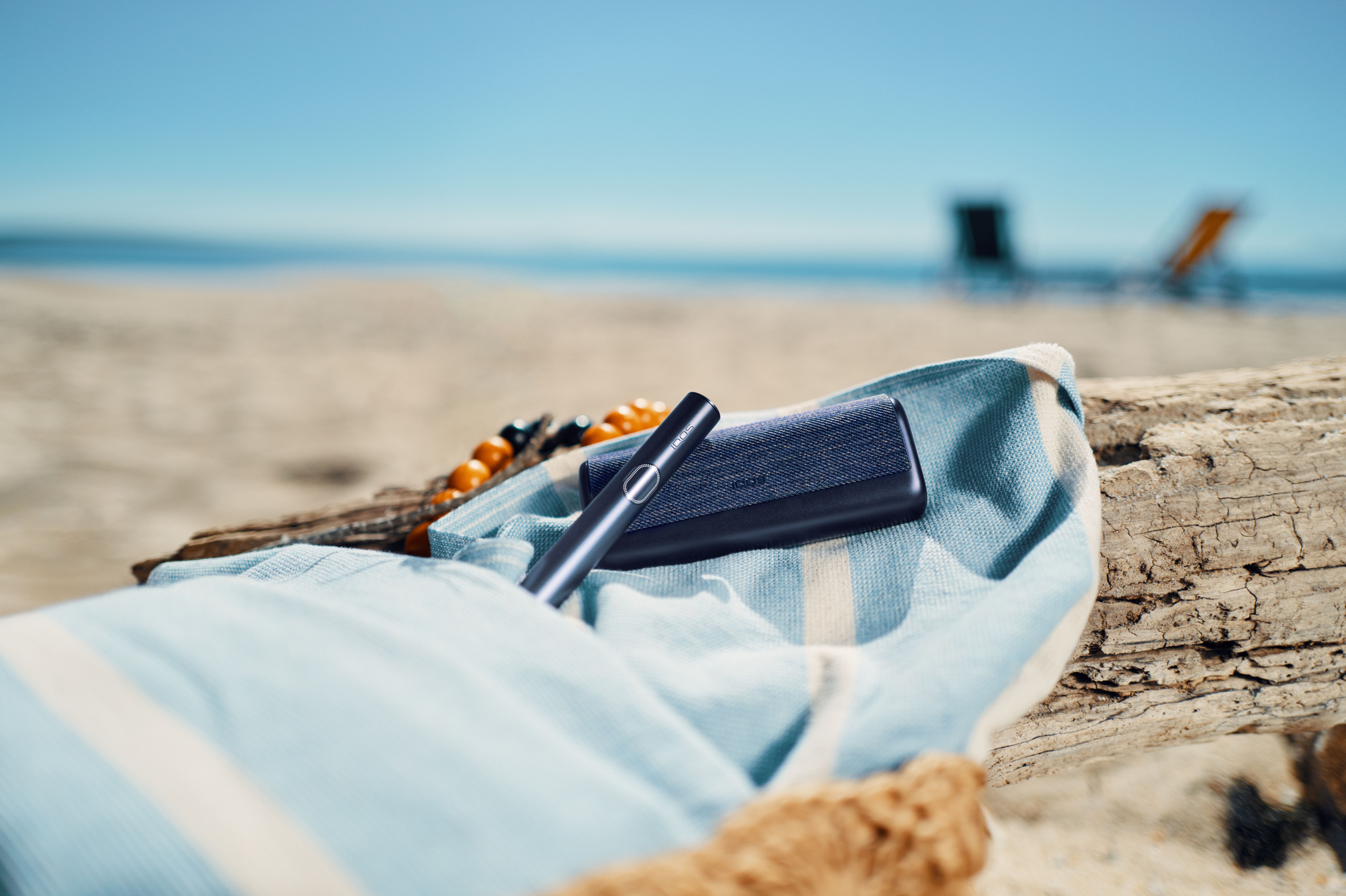 Dispositivo Iqos sobre una toalla en la playa