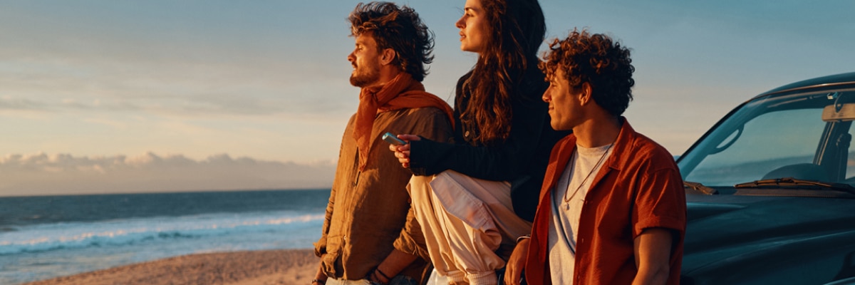 Tres personas en la playa con un IQOS ILUMA i ONE breeze blue