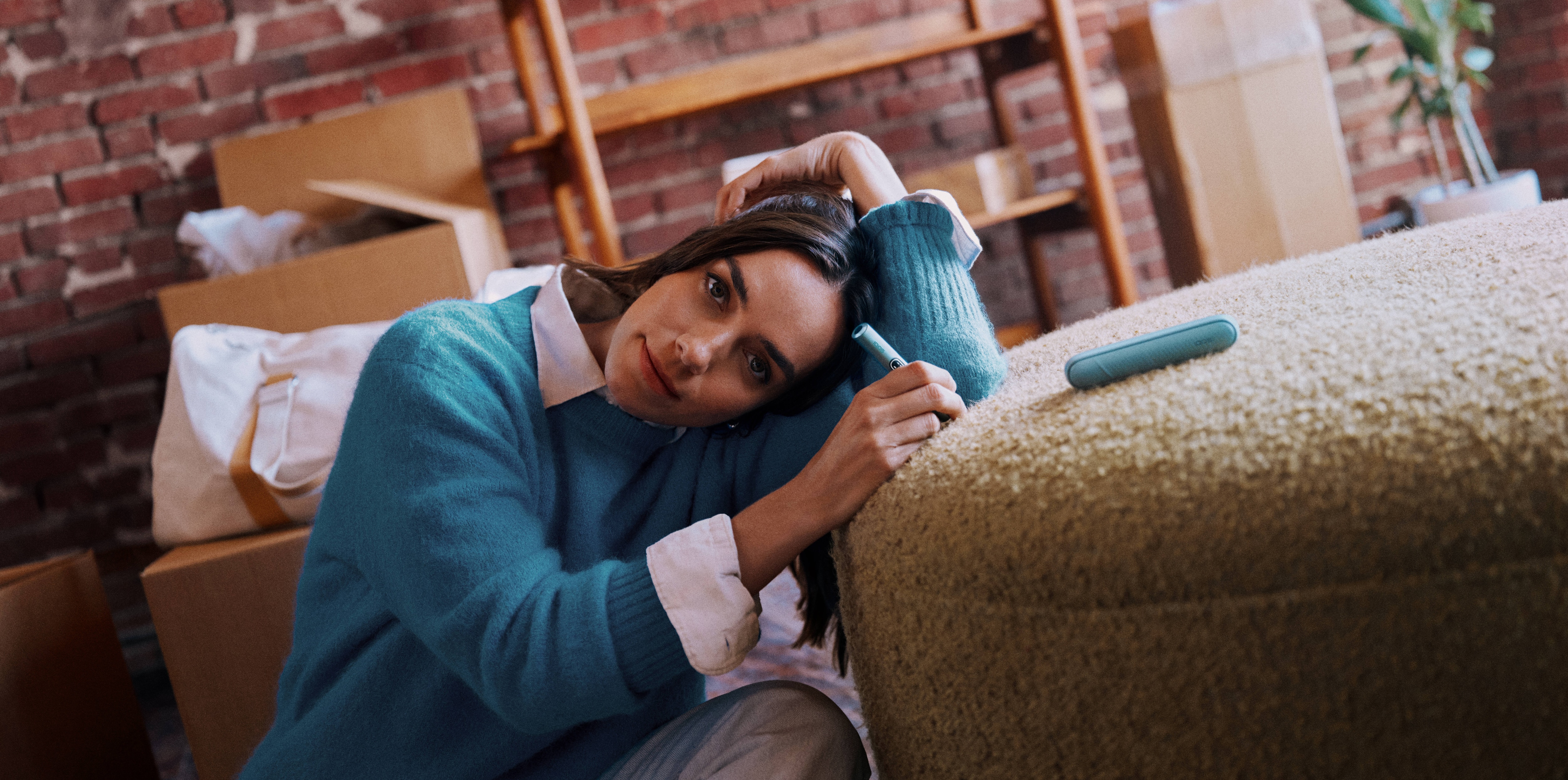Mujer recostada en un sofa con un IQOS