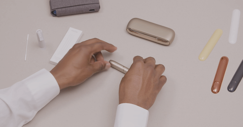 Man removes IQOS 3 DUO golden cap to clean device