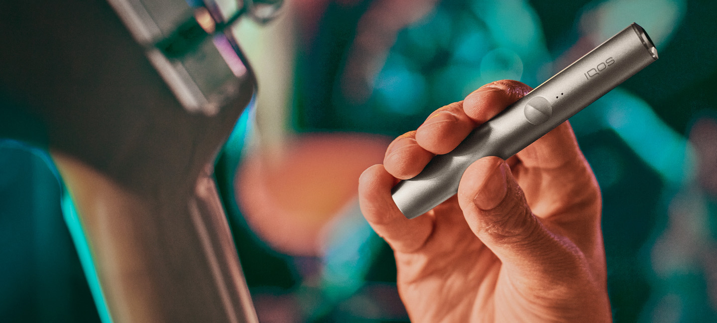 A person holding an IQOS ILUMA device.