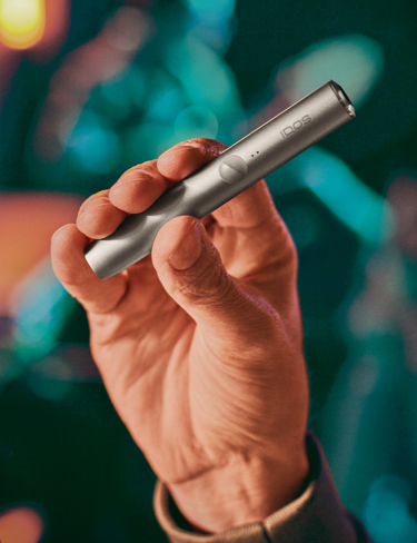 A person holding an IQOS ILUMA device.