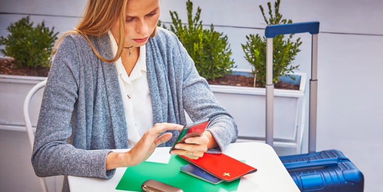 A woman using a mobile phone; her passport and IQOS device nearby.