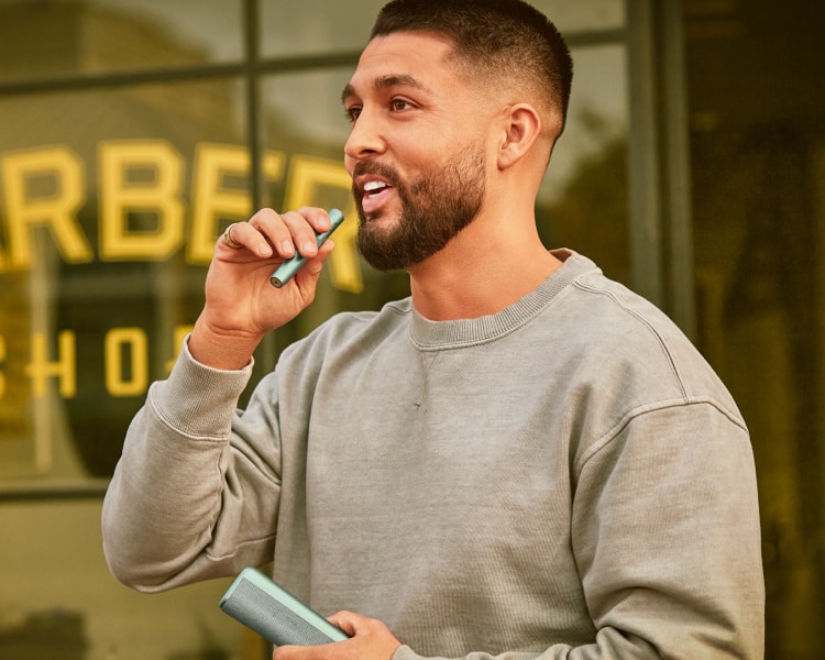 A man holding an IQOS device near his mouth.
